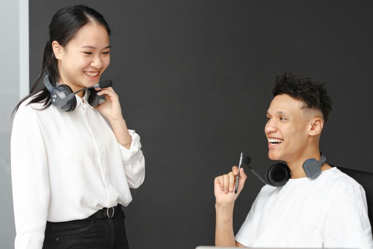 Two colleagues engaging in a friendly conversation with headsets in an office setting.